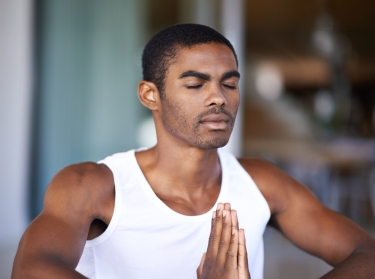 African American male meditating at home