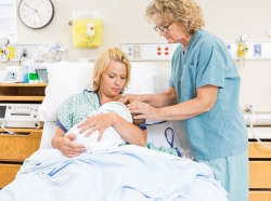 Female nurse assisting a breastfeeding mother in the hospital