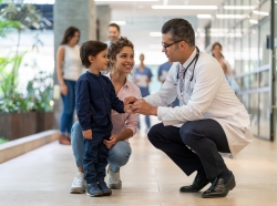 Male pediatrician talking to a young boy and his mother, photo by Hispanolistic/Getty Images