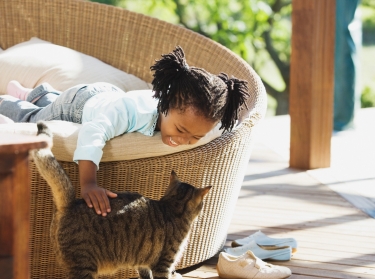 Young girl petting a cat on a veranda