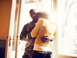 African American soldier and his wife embracing in a sunny doorway