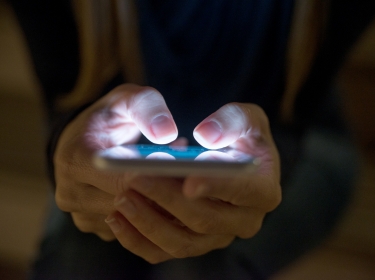 Close up of a person's hands using a mobile phone at night