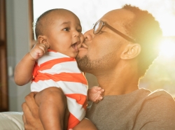 Father kisses baby son on cheek