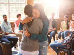 Women hugging in a group therapy session