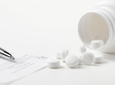 Pen, prescription, and spilled bottle of white pills