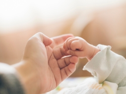 Newborn hand holding the finger of an adult hand, photo by deng qiufeng/Getty Images