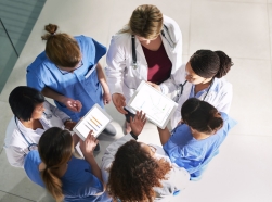 Group of medical practitioners in a circle, talking, seen from above, photo by Cecilie_Arcurs/Getty Images