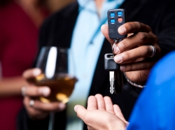 Close-up of a man holding a drink with one hand and giving his keys to another person, photo by avid_creative/Getty Images