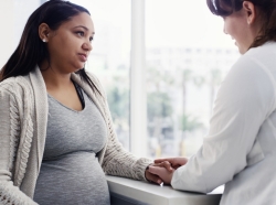 Female doctor talking to a pregnant woman, photo by LumiNola/Getty Images