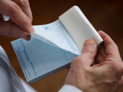 Closeup of a doctor tearing a prescription off a pad, photo by wdstock/Getty Images