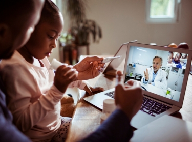 Father and daughter having a video call with their doctor, photo by Geber86/Getty Images