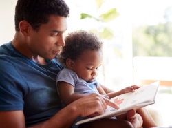 Young Black father reading to toddler, photo by monkeybusinessimages/Getty Images
