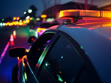 Close up of a police car at a nighttime traffic stop, photo by RichLegg/Getty Images