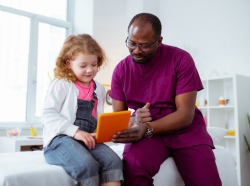 Pediatrician showing cartoon on tablet for his little patient, photo by Viacheslav Lakobchuk/Adobe Stock