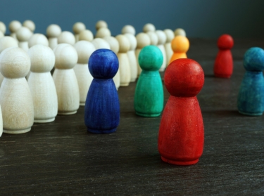 Colored wooden figurines against rows of white figurines, photo by designer491/Getty Images