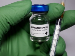 Gloved hand holding a vial of buprenorphine and a syringe, photo by Hailshadow/Getty Images