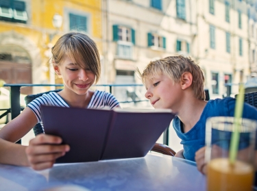 A young girl and boy look at a restaurant menu