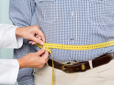 Doctor measuring a man's stomach with measuring tape