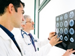 Two male doctors examine an MRI scan of the brain