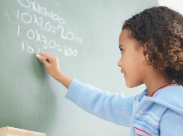 Girl doing multiplication on a chalkboard