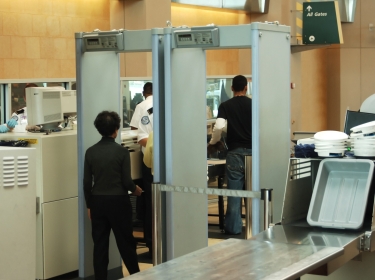 airport security check with passenger walking through metal detector