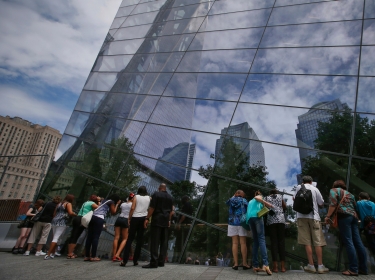 Visitors to the 911 Memorial plaza peer through glass windows into the 911 Memorial Museum at the World Trade Center site in New York