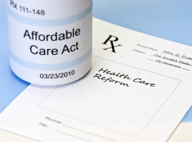 A prescription bottle labeled Affordable Care Act and prescription pad