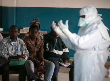 A health worker demonstrates putting on protective gear in a Red Cross facility in Koidu, Sierra Leone, December 18, 2014