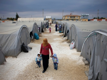 A Kurdish refugee woman from Syria walks with her children at a refugee camp in Suruc, Turkey, November 17, 2014