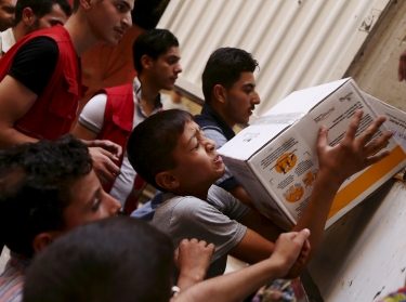 Boys help members of the Syrian Arab Red Crescent unload parcels of medical and humanitarian aid in Damascus, Syria, July 23, 2015