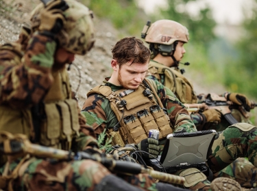 Soldiers using laptop outdoors