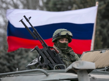 A Russian soldier on top of an army vehicle keeps watch outside a border guard post in the Crimean town of Balaclava, March 1, 2014