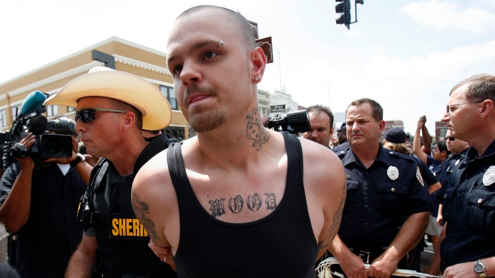 A white supremacist protester is escorted away in handcuffs by a sheriff during a demonstration in Paris, Texas, July 21, 2009, photo by Jessica Rinaldi/Reuters
