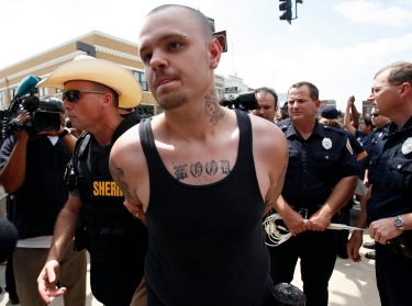 A white supremacist protester is escorted away in handcuffs by a sheriff during a demonstration in Paris, Texas, July 21, 2009, photo by Jessica Rinaldi/Reuters