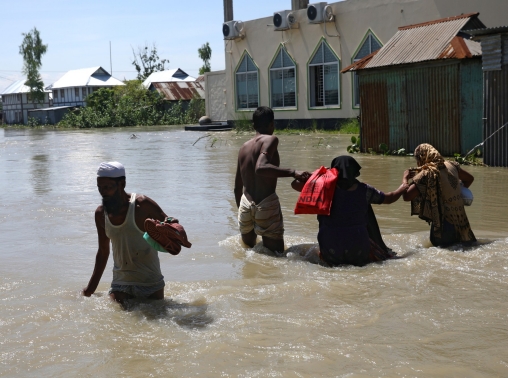 People walk on flooded land beside the Padma River as a flood worsens on the outskirts of Dhaka, Bangladesh, July 25, 2020