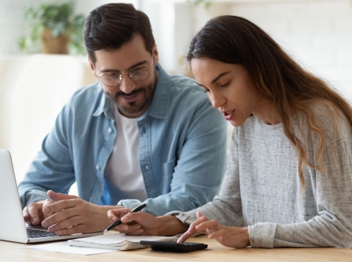 A couple managing their finances using a laptop and calculator