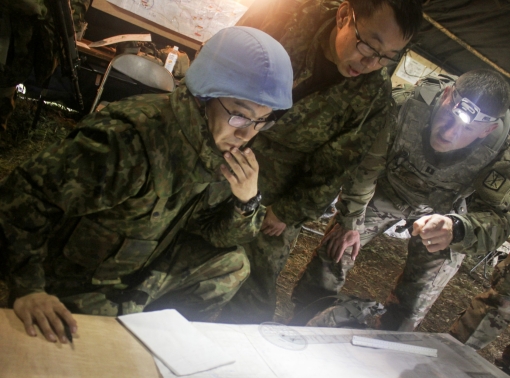 Members of the Japan Ground Self-Defense Force and a U.S. Army captain examine a field artillery safety diagram at Yausubetsu Training Area, Japan, photo by U.S. Army