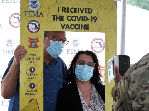 People pose for a photo after being vaccinated at the FEMA-supported COVID-19 vaccination site at Valencia State College in Orlando, Florida