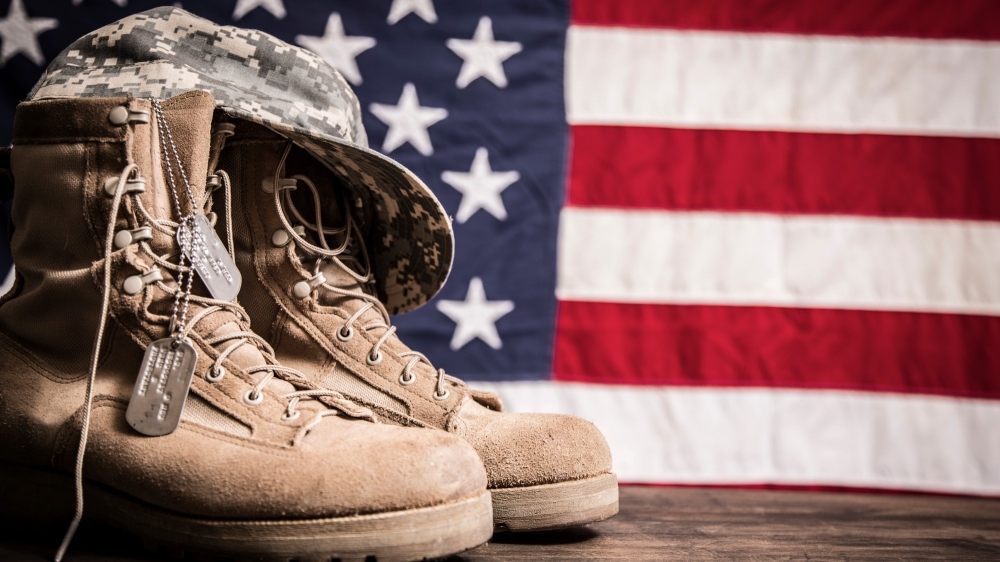 USA military boots, hat and dog tags with American flag in background. Photo by fstop123/Getty Images