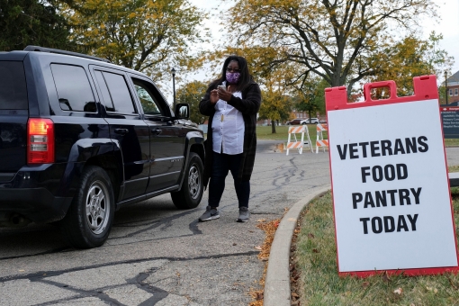 A worker checks the identification of a veteran receiving aid at a food bank in Dayton, Ohio, October 15, 2020