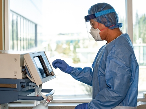 A respiratory therapist operates a ventilator in the intensive care unit