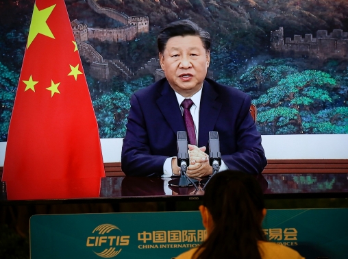 A journalist sits next to a screen showing Chinese President Xi Jinping delivering a speech via video for the opening ceremony of the 2020 China International Fair for Trade in Services (CIFTIS), at a media centre in Beijing, China September 4, 2020