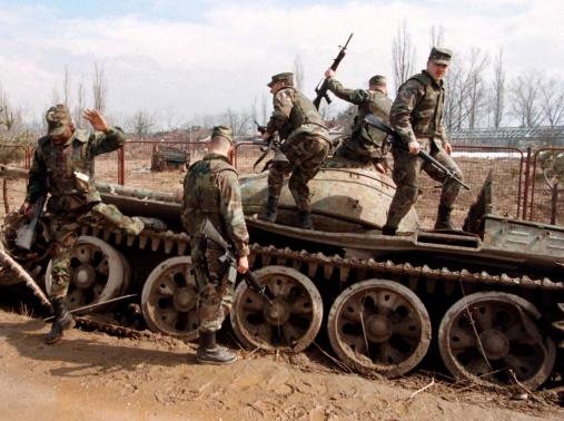 A group of U.S. NATO Implementation Force (IFOR) soldiers climb off a destroyed Bosnian tank March 16, 1996