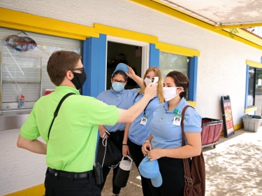 The front gate admissions supervisor checks employees' temperatures before the start of their shifts at Golfland Sunsplash water park in Mesa, Arizona, May 15, 2020, photo by Caitlin O'Hara/Reuters