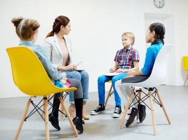 Three elementary school children and a teacher sitting in a circle