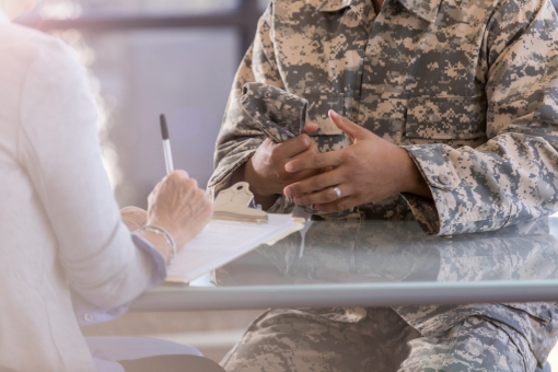 A mental health professional takes notes while talking with a soldier