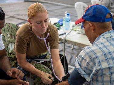 A nurse assigned to the hospital ship USNS Comfort takes a man's blood pressure