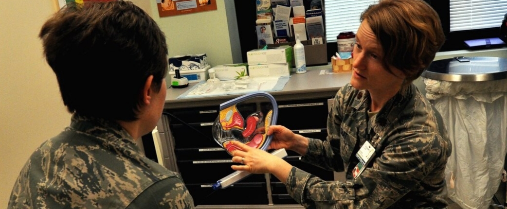 An Air Force OB/GYN physician holds a model of the female reproductive organs