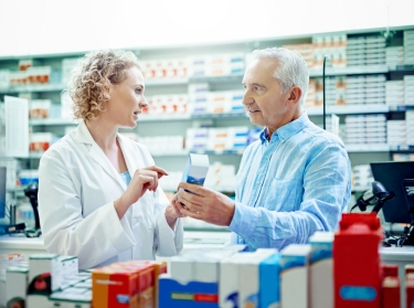 Female pharmacist talking to an elderly man about a prescription