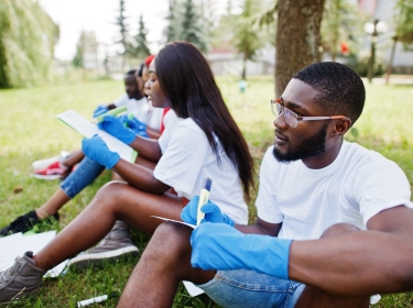 Black volunteers review paperwork in a park, photo by AS photo/Adobe Stock